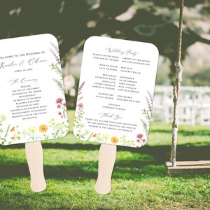 Puede incluir: Abanicos de programa de ceremonia de boda con un diseño floral. Los abanicos presentan una ilustración de acuarela de flores silvestres y vegetación. El texto en los abanicos incluye los nombres de la novia y el novio, la fecha de la boda y el orden de la ceremonia. Los abanicos también incluyen una lista de la fiesta de bodas.