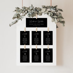 May include: Black and white wedding seating chart with the names "Luella & Wilder" and the date "September 15, 2014". The chart is hung on a white wall with greenery hanging from the top.