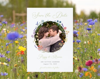 May include: Save the date card with a floral wreath design. A photo of a couple kissing is in the center of the wreath. The text on the card reads "Save the Date", "Poppy & Rowan", "Are Getting Married", "August 7th, 2022", and "Formal Invitation to Follow".