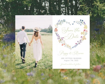 May include: Save the date card with a floral heart design. The card features a watercolor illustration of a heart made of colorful flowers. The text "Save the Date" is written in gold script. The names "Poppy & Rowan" are written below the heart. The text "Are getting married" is written below the names. The date "August 7th, 2022" is written below the text. The text "Formal invitation to follow" is written below the date.