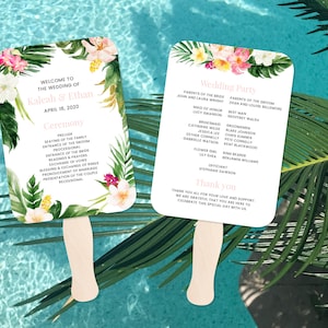 May include: Two white wedding fans with tropical floral designs and text. The left fan says "Welcome to the wedding of Kaleah & Ethan April 18, 2020" and lists the ceremony order. The right fan says "Wedding Party" and lists the names of the wedding party members.