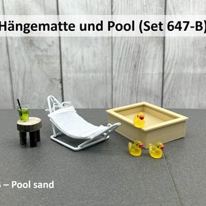 Könnte beinhalten: Miniatur-Set mit einem weißen Metall-Liegestuhl mit weißem Stoffbezug, einem kleinen Holztisch mit einem Getränk und einem rechteckigen Pool mit gelben Gummienten. Das Set trägt die Bezeichnung "Hängematte und Pool".