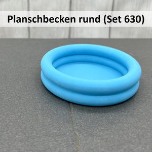 Könnte beinhalten: Ein kleines, rundes, hellblaues Planschbecken. Der Pool hat zwei gestapelte kreisförmige Ringe. Der Text "Planschbecken rund (Set 630)" befindet sich in einem weißen Rechteck.
