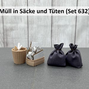 Könnte beinhalten: Ein Miniatur-Set von Müllgegenständen, darunter ein geflochtener Korb mit weißen Gegenständen, ein rechteckiger Korb mit silbernen Gegenständen und zwei dunkelblaue Kordelzugbeutel. Der Text "Müll in Säcke und Tüten (Set 632)" steht oben.