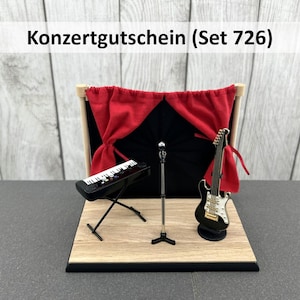 Könnte beinhalten: Miniatur-Bühnenbild mit einem schwarzen Keyboard, einer schwarz-weißen E-Gitarre und einem Mikrofonständer. Ein roter Vorhang hängt im Hintergrund. Der Text "Konzertgutschein (Set 726)" wird oben angezeigt.