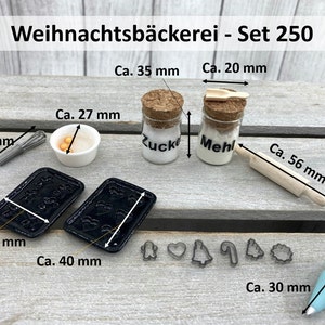 K&ouml;nnte beinhalten: Miniatur-Backset mit dem Text "Weihnachtsb&auml;ckerei - Set 250". Enth&auml;lt zwei kleine Gl&auml;ser mit der Aufschrift "Zucker" und "Mehl", ein Nudelholz (5,6 cm), Ausstecher, einen Schneebesen (3,2 cm), eine Sch&uuml;ssel, zwei Backbleche (4 cm x 3 cm) und einen Spritzbeutel.