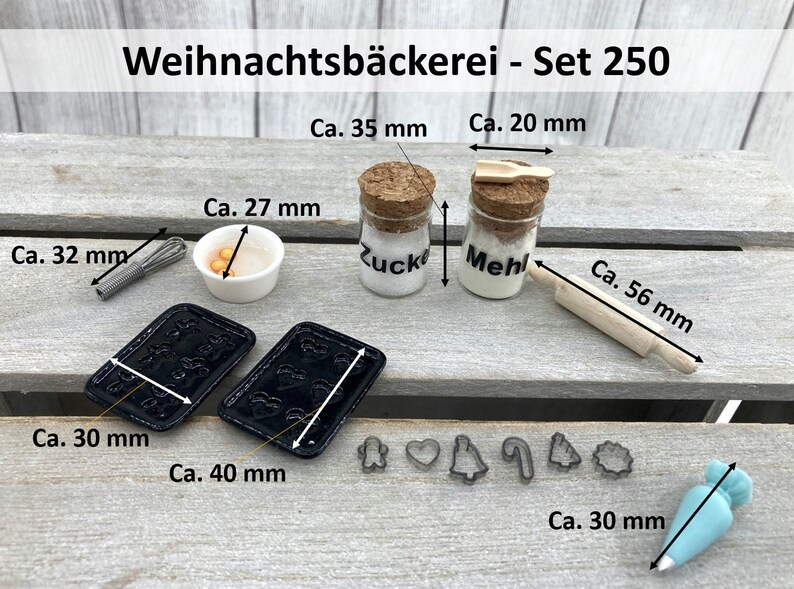 K&ouml;nnte beinhalten: Miniatur-Backset mit dem Text "Weihnachtsb&auml;ckerei - Set 250". Enth&auml;lt zwei kleine Gl&auml;ser mit der Aufschrift "Zucker" und "Mehl", ein Nudelholz (5,6 cm), Ausstecher, einen Schneebesen (3,2 cm), eine Sch&uuml;ssel, zwei Backbleche (4 cm x 3 cm) und einen Spritzbeutel.