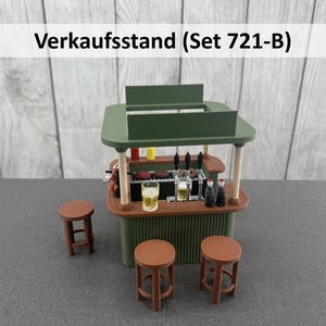 Könnte beinhalten: Miniatur-Bar in Grün und Braun mit drei braunen Hockern. Die Bar hat ein grünes Dach, eine braune Theke und einen grünen Sockel. Die Bar ist mit Miniaturflaschen, Gläsern und Zapfhähnen bestückt. Der Text "Verkaufsstand (Set 721-B)" steht über der Bar.