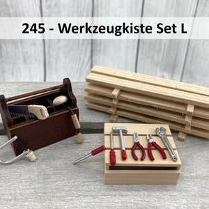 Könnte beinhalten: Eine Miniatur-Holzkiste mit einer Säge, einem Hammer, einer Zange und einem Schraubenschlüssel. Die Werkzeugkiste ist mit "245 - Werkzeugkiste Set L" beschriftet.