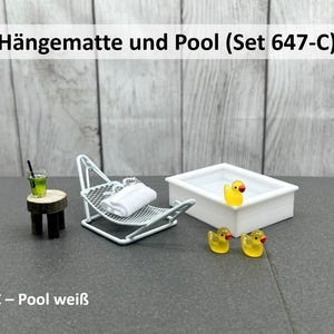 Könnte beinhalten: Miniatur-Hängematte mit weißem Handtuch, kleiner Holztisch mit grünem Getränk und weißem Pool mit gelber Quietscheente. Zwei weitere gelbe Enten sind ebenfalls vorhanden. Der Text "Hängematte und Pool (Set 647-C)" ist sichtbar.