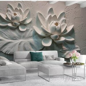 K&ouml;nnte beinhalten: Eine wei&szlig;e 3D-Wandmalerei mit zwei gro&szlig;en wei&szlig;en Lotusblumen mit Bl&auml;ttern. Die Wandmalerei ist in einem Wohnzimmer mit einem wei&szlig;en Sofa und einem Couchtisch dargestellt.