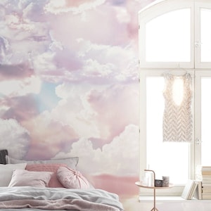 Könnte beinhalten: Ein Schlafzimmer mit einer rosa-weißen Wolkentapete, einem Bett mit weißen und rosa Kissen, einem Nachttisch mit einer Lampe und einem Fenster mit einem weißen Kleid, das daran hängt.