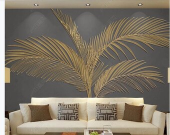 Puede incluir: Una pared gris con un gran diseño de hojas de palmera doradas. Un sofá blanco con cojines marrones está delante de la pared.
