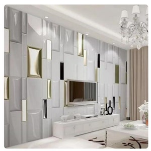 Könnte beinhalten: Eine weiße Wand mit einem geometrischen Muster aus weißen, goldenen und schwarzen Fliesen. Ein Flachbildfernseher ist an der Wand über einem weißen Unterhaltungszentrum mit Schubladen montiert.
