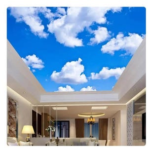 May include: A white ceiling with a blue sky and white clouds printed on it. The ceiling is in a room with white walls and a chandelier.