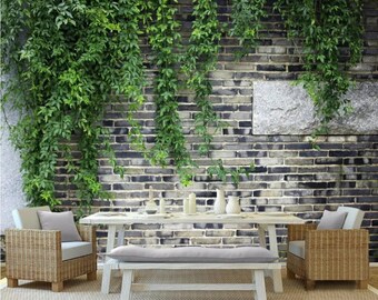 May include: A brick wall covered in green ivy with a white wooden bench and two wicker chairs with cushions. The chairs and bench are in front of a table with a white top and a gray brick wall background.