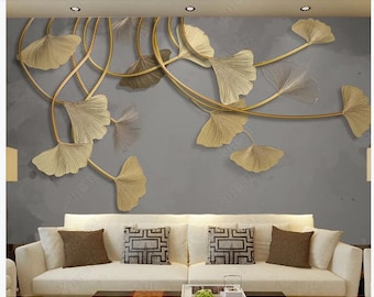 Puede incluir: Una pared gris con una escultura de pared de metal dorado de hojas de ginkgo estilizadas. La escultura está colgada sobre un sofá blanco con dos almohadas.