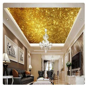 May include: A living room interior with a gold glitter ceiling. The ceiling is covered in a sparkling gold wallpaper. The room has a black leather sofa, a coffee table, and a chandelier.