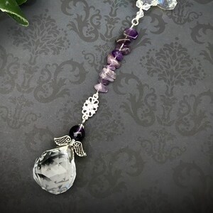 May include: A crystal suncatcher with an angel charm and amethyst beads. The suncatcher is made of clear crystal and has a faceted design. The amethyst beads are purple and are strung on a silver chain.