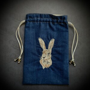 May include: A dark blue drawstring bag with a white embroidered rabbit on the front.