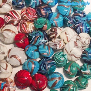 May include: A collection of colorful glass beads with swirling patterns and gold accents. The beads are handmade and have a unique, artisan look.