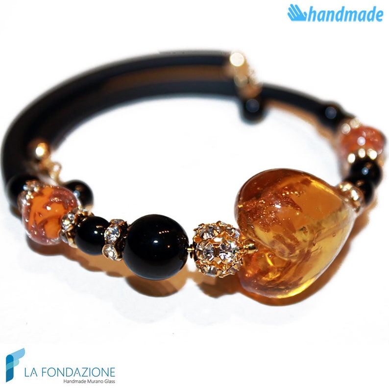 Puede incluir: Un brazalete el&aacute;stico negro con un gran dije de coraz&oacute;n de &aacute;mbar, cuentas negras y una peque&ntilde;a cuenta dorada con pedrer&iacute;a.