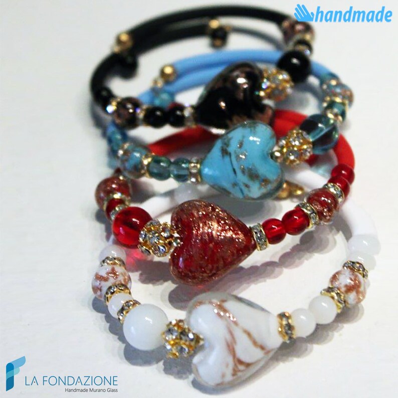 May include: Five colorful bracelets with heart-shaped Murano glass beads. The bracelets are layered on top of each other, with the white bracelet on the bottom and the black bracelet on the top. The heart-shaped beads are in shades of red, blue, white, and black.