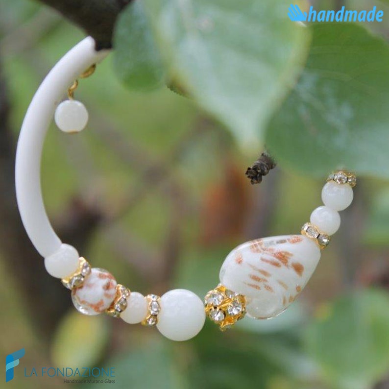 May include: White hoop earrings with a gold accent and white and brown glass beads. The beads are decorated with gold and rhinestones. The earrings are handmade.