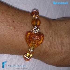 May include: A gold and amber glass heart charm bracelet with clear rhinestones. The bracelet is handmade and features a Murano glass heart charm.