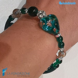 May include: A green glass heart charm bracelet with silver beads and a green elastic band. The bracelet is handmade and features a Murano glass heart charm.
