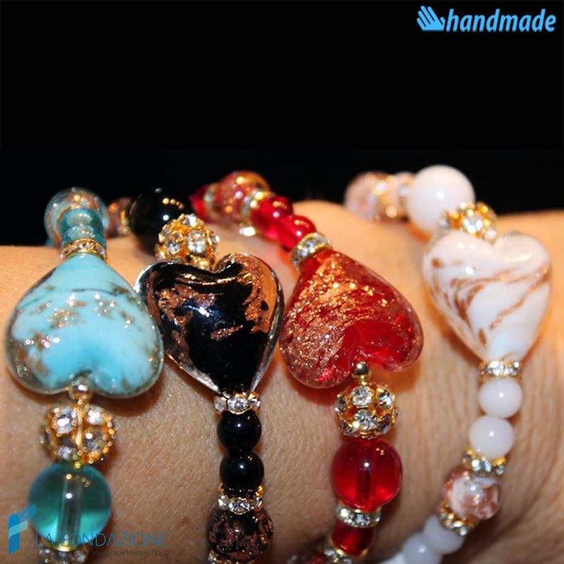 May include: Four bracelets with heart-shaped glass beads. The beads are in shades of turquoise, black, red, and white with gold flecks. The bracelets are made with small round beads and rhinestones.