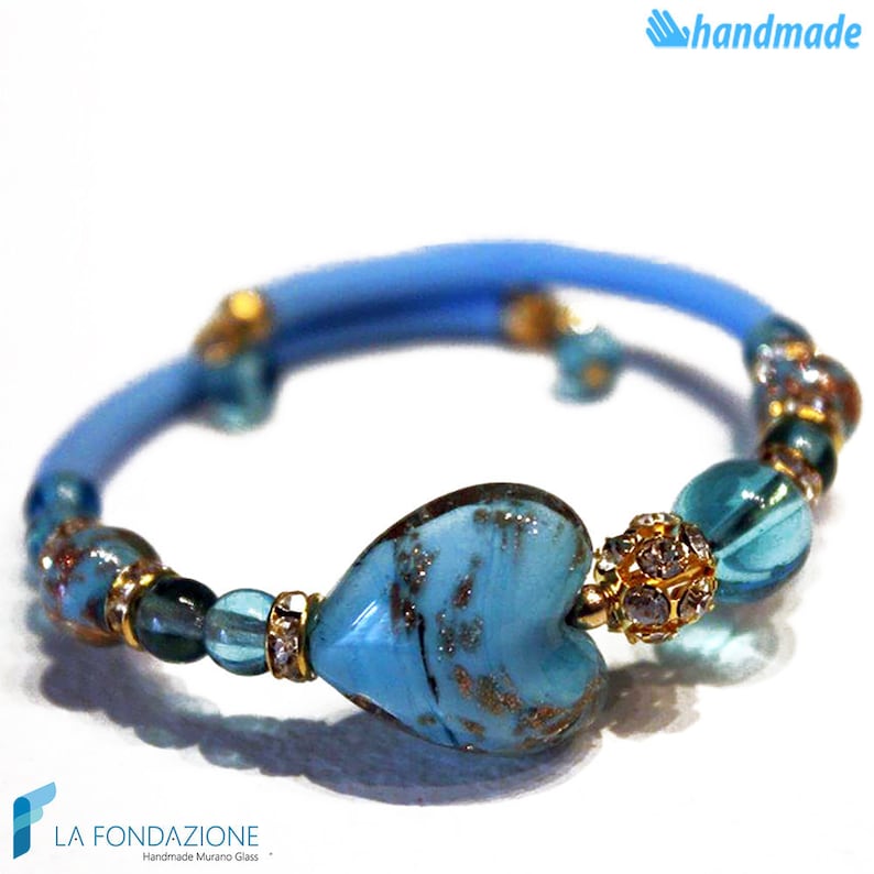 May include: A blue and gold bracelet with a heart-shaped Murano glass charm. The bracelet is made with blue cord and features small blue and gold beads.