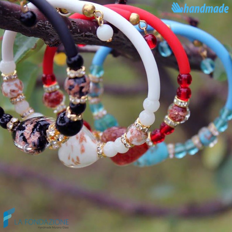 May include: Five colorful bracelets with glass beads and gold accents. The bracelets are made of different colored silicone and are strung with various colored glass beads. The bracelets are handmade and feature the text "handmade".