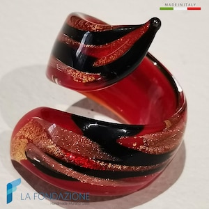 Peut inclure: Une bague en verre rouge, noir et or avec un motif en spirale. La bague est fabriquée en Italie et est en verre de Murano fait main.