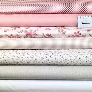 Könnte beinhalten: Ein Stapel aus sechs verschiedenen rosa und weißen Stoffmustern. Die Stoffe umfassen ein rosa Netz, ein einfarbiges Rosa, einen Blumendruck, einen Gingham-Karo, einen kleinen Blumendruck und einen weißen Stoff mit kleinen grauen Punkten.