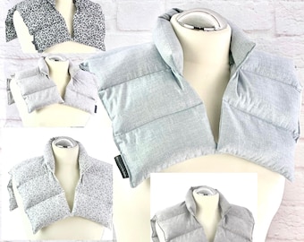 Puede incluir: Una colección de cinco almohadillas térmicas para cuello y hombros exhibidas en maniquíes. Las almohadillas presentan varios patrones de tela, incluyendo estampado de leopardo, gris claro y diseños grises texturizados, con una construcción acolchada.