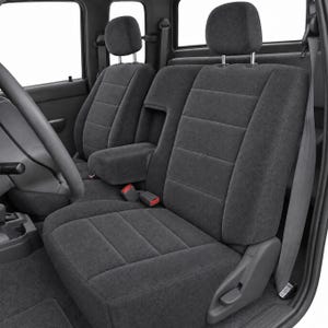 May include: A set of dark gray fabric seat covers installed on vehicle seats. The covers feature horizontal stitched lines, adjustable headrests, and a center console armrest. The design includes integrated seat belt buckles and side levers.