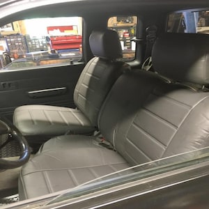 May include: Two gray leather car seats with headrests in a vehicle interior. The seats have a diamond-stitched pattern.