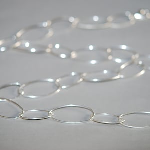 Puede incluir: Un collar de cadena de plata hecho de eslabones grandes de forma ovalada.