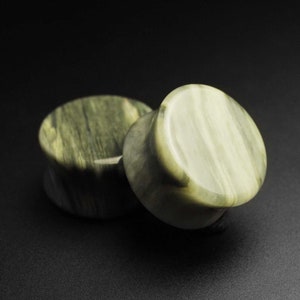 以下が含まれることがあります： 緑と白の石製の耳ゲージ2個。ゲージは丸型で、滑らかで磨かれた仕上げになっています。