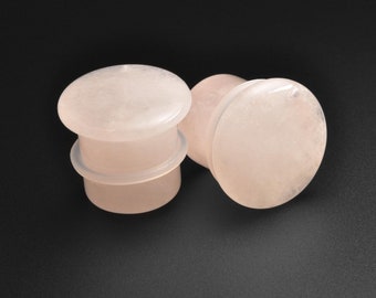 May include: Two pairs of pink stone ear gauges. The gauges are round and have a smooth, polished finish.