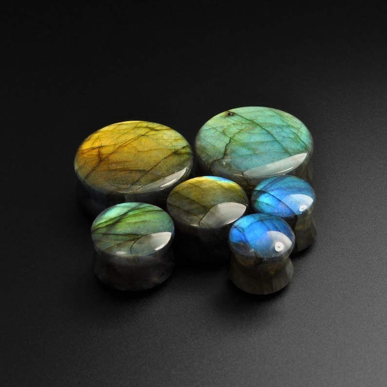 May include: A set of six iridescent labradorite stone ear gauges in various sizes. The gauges are a mix of blue, green, and gold colors.