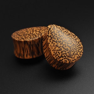 May include: Two wooden ear gauges with a brown and black patterned design. The gauges are made of wood and have a natural finish.