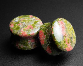 Puede incluir: Dos tapones para orejas de piedra verde, rosa y blanca. Los tapones son redondos y tienen un acabado liso y pulido.