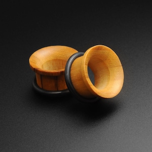 May include: Two wooden ear gauges with black rubber o-rings. The gauges are a light brown colour and have a smooth, polished finish.