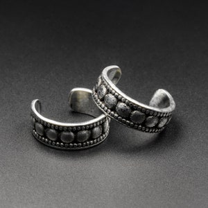 Puede incluir: Dos pendientes de plata con diseño de cuentas. Los pendientes están abiertos y tienen una forma redondeada.