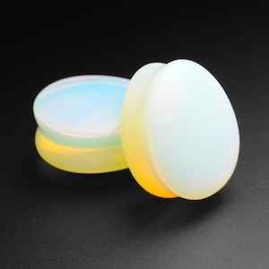 Op de afbeelding: Twee iriserende oorstekers van opaal, de ene is een lichtere tint opaal en de andere is een donkerdere tint opaal.