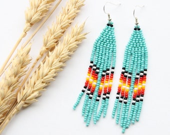 May include: Teal blue beaded earrings with black, red, orange and yellow accents. The earrings are long and dangle.
