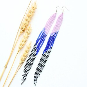 May include: A pair of long, beaded earrings with a gradient of pink, blue, and black beads. The earrings are hanging from silver hooks.