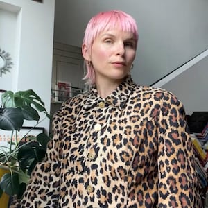 May include: A long-sleeved jacket featuring a brown and black leopard print pattern, a standard collar, and a front button closure with metallic gold-toned buttons. The jacket is paired with blue denim jeans, creating a casual ensemble.